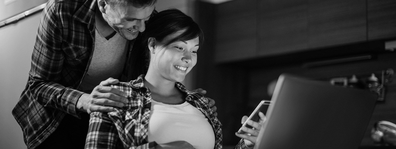 A couple using a smartphone and laptop